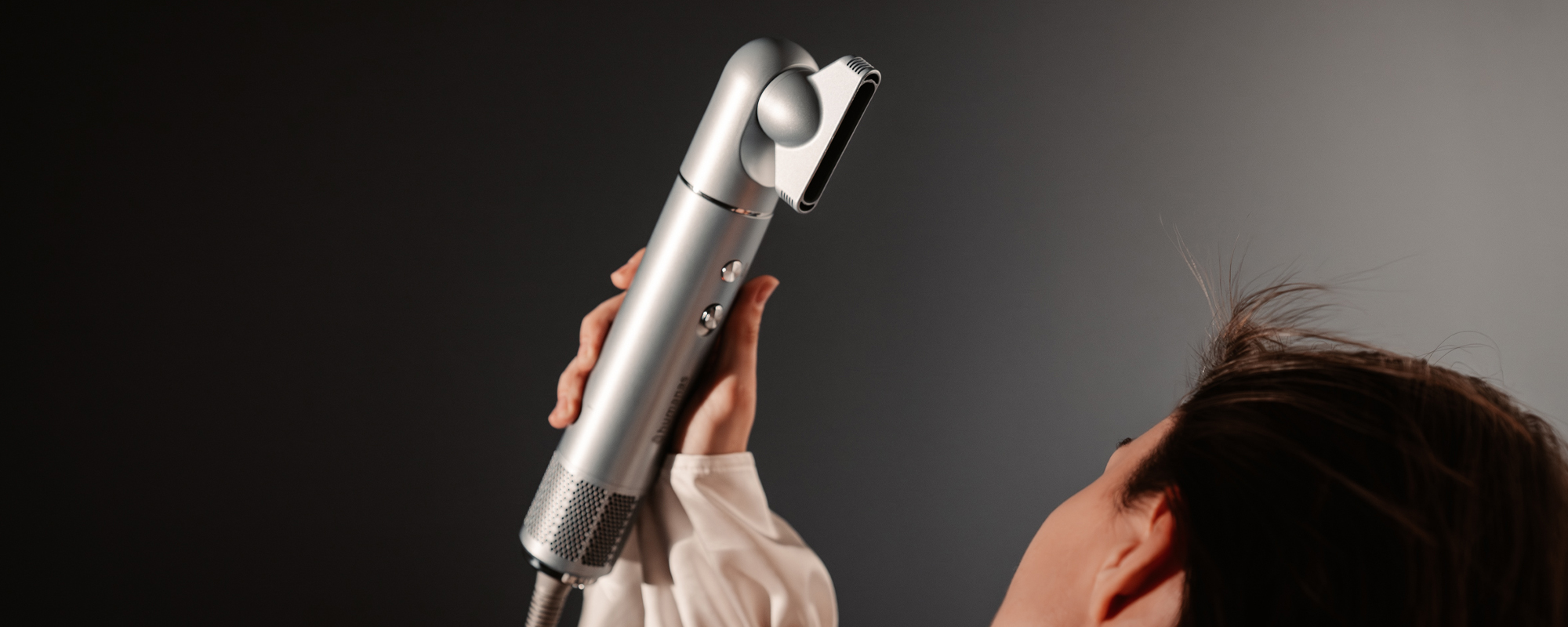 Srebrna suszarka do włosów z funkcją jonizowania Humanas AirTouch HD-AT05 skierowana w stronę głowy modelki